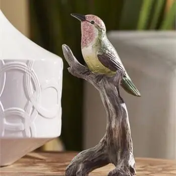 resin bird sitting on a branch with a pink face